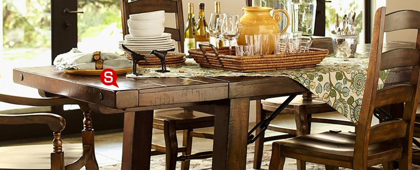 Rustykalne wnętrze salonu z drewnianym, zastawionym stołem. Naturalna kolorystyka to kwintesencja stylu rustykalnego.